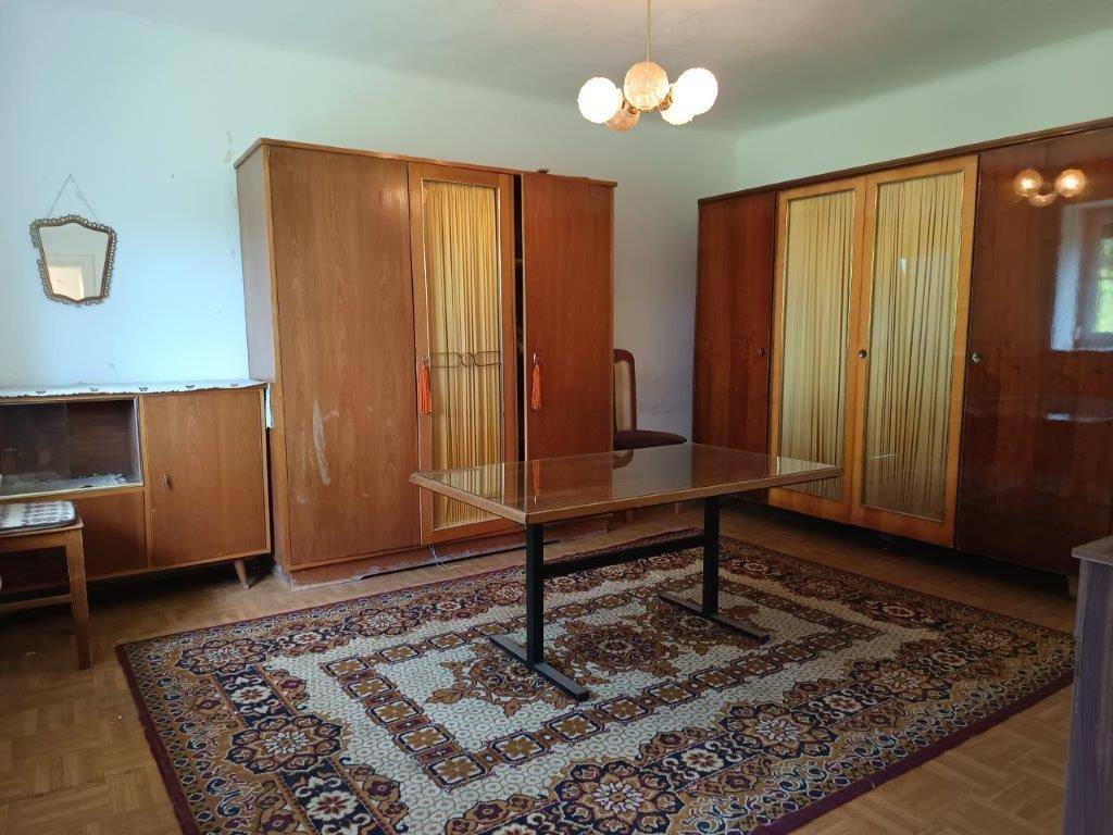 Geräumiges Zimmer mit Holzschränken, Teppich und einem Tisch in der Mitte, ideal als Schlafzimmer.