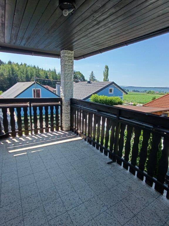 Geräumiger Balkon mit Fliesenboden und Holzgeländer, bietet einen weiten Blick auf die Umgebung.