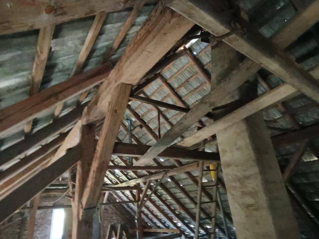 Blick in die komplexe Holzkonstruktion eines alten Dachbodens mit zahlreichen freiliegenden Balken.