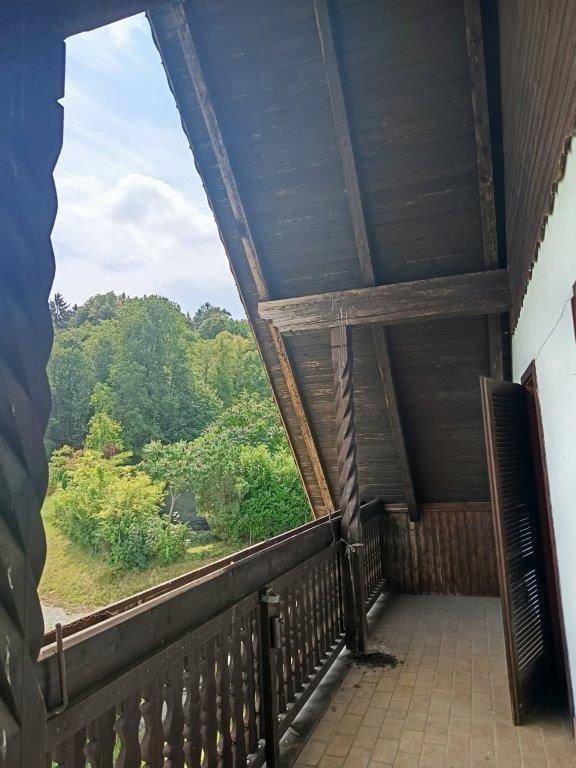 Geräumiger Holzbalkon mit Fliesenboden und weitem Blick auf die grüne Hügellandschaft.
