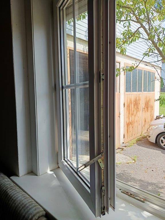 Geöffnetes Fenster mit Blick auf eine Garage und den Außenbereich, bietet frische Luft.