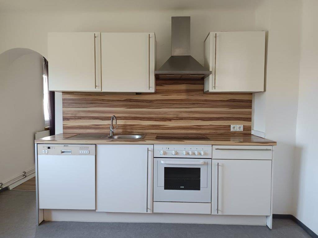 Funktionale Einbauküche mit weißen Fronten, Spülmaschine, Backofen und Dunstabzugshaube.