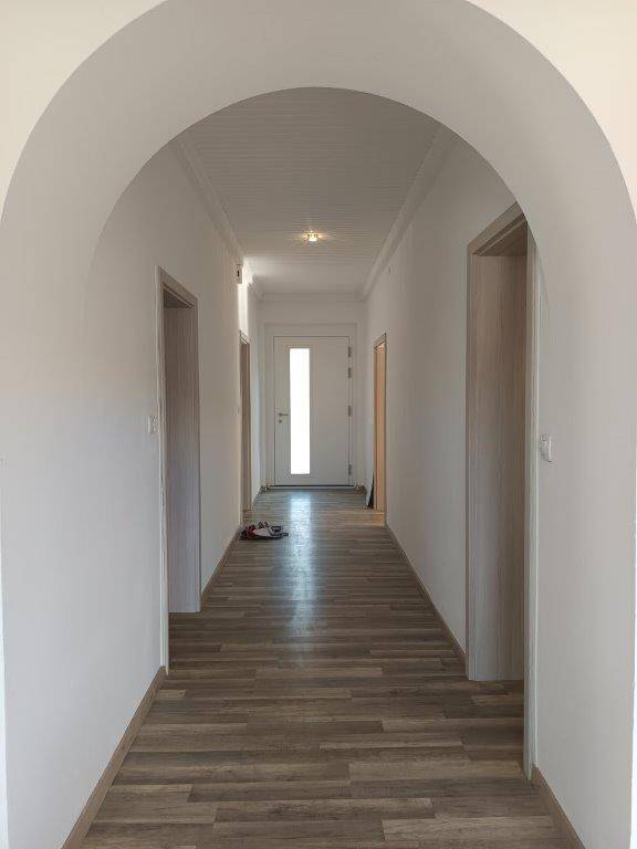 Langer, heller Flur mit Laminatboden und eleganten Rundbögen, der zu verschiedenen Zimmern führt.