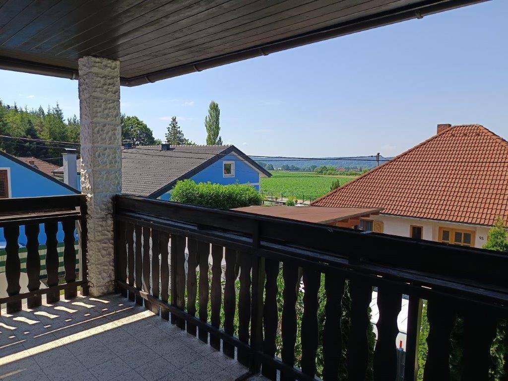 Balkon mit traditionellem Holzgeländer und Fliesenboden bietet einen weiten Blick über die Landschaft.