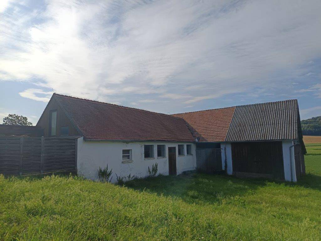 Rückansicht der ländlichen Gebäude mit roten Ziegeldächern und angrenzendem Feld.