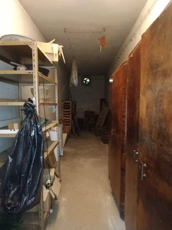 Schmaler Lagerraum im Keller mit Regalen und alten Schränken, der zur Aufbewahrung dient.