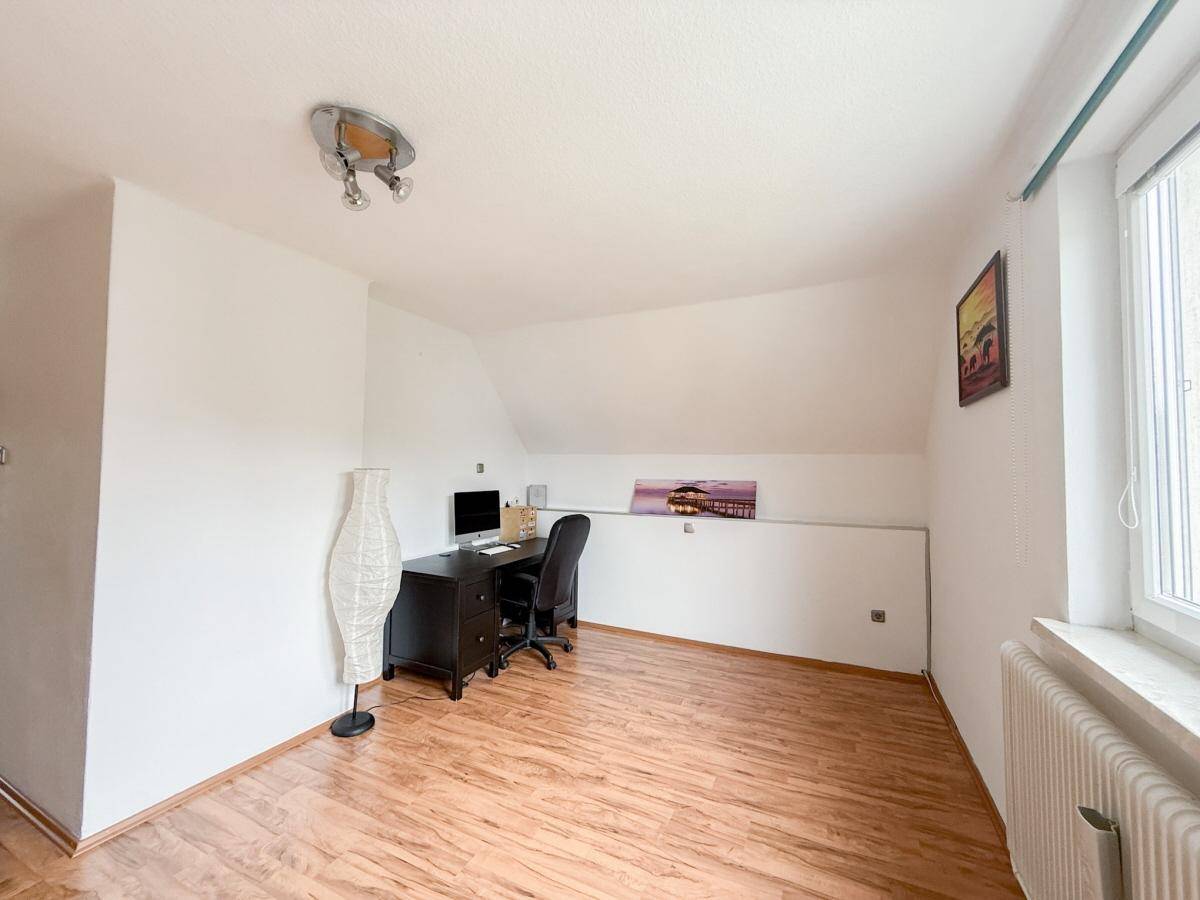 Helles Dachzimmer mit Schreibtisch, Computer und Laminatboden, ideal als Büro oder Gästezimmer.