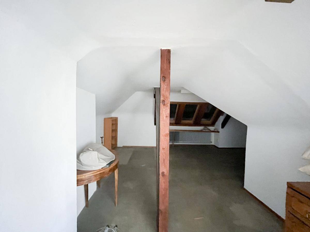 Ausgebauter Dachboden mit schrägen Wänden, Holzbalken und Dachfenstern.
