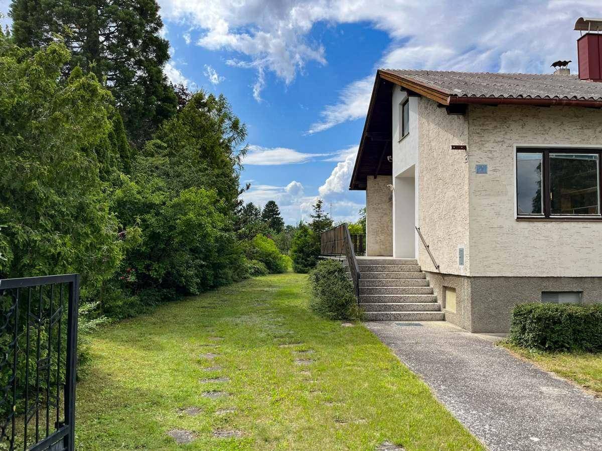 Seitenansicht des Hauses mit Zufahrt und einem gepflegten Gartenbereich.