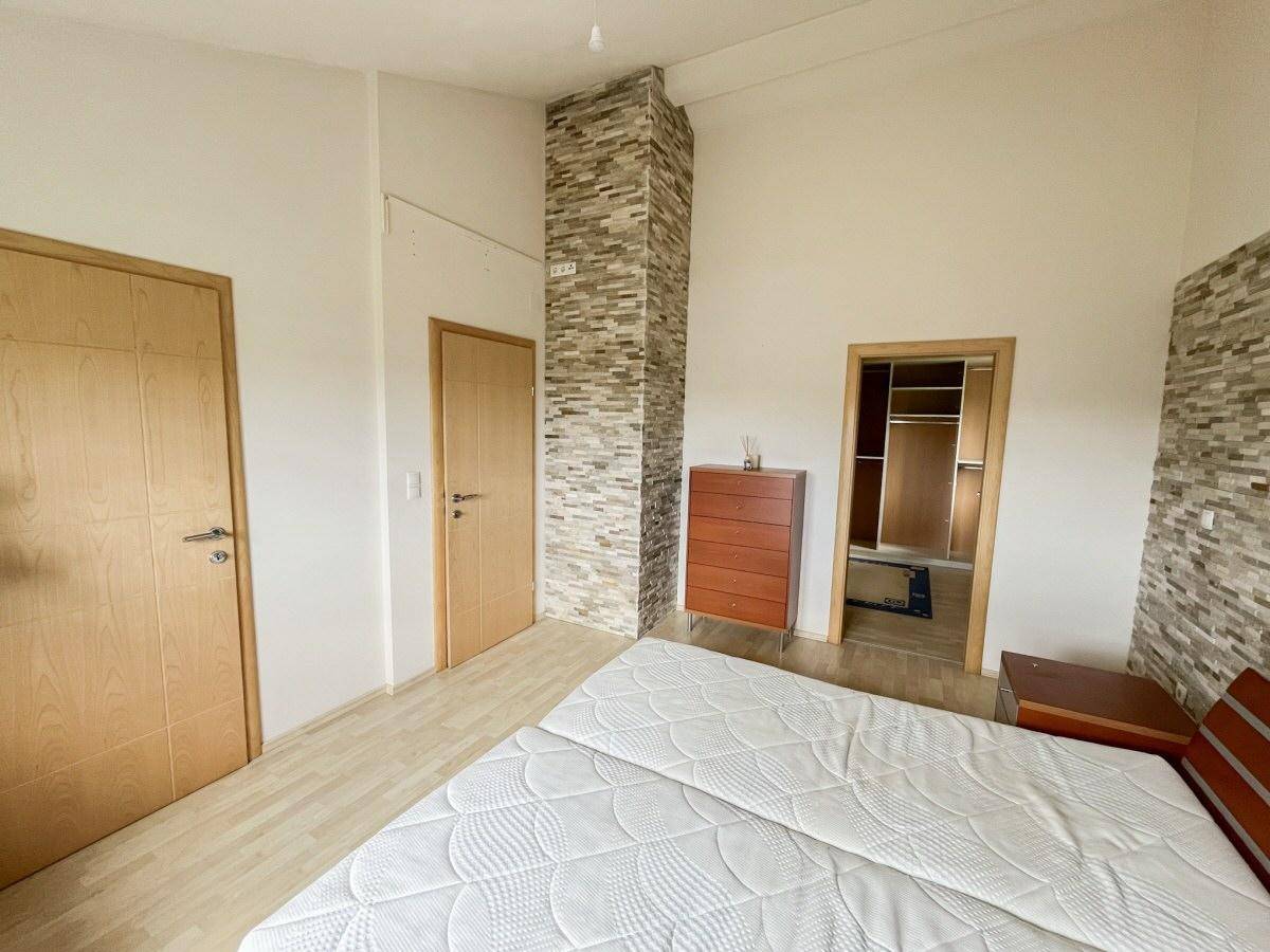 Schlafzimmer mit Doppelbett, Holzboden und dekorativer Steinwand.
