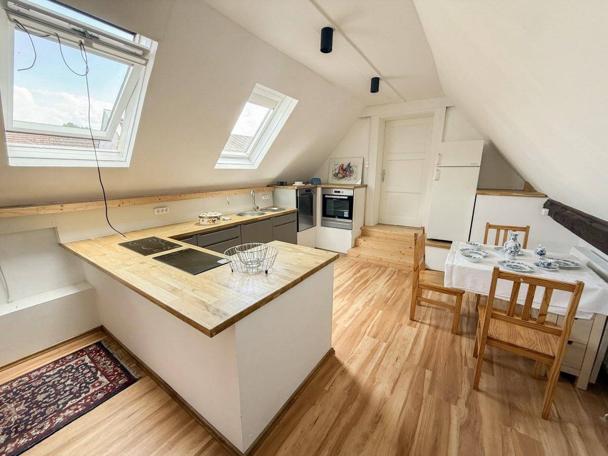 Moderne Dachgeschossküche mit Kochinsel, Holzarbeitsplatten, Essbereich und Dachfenstern.