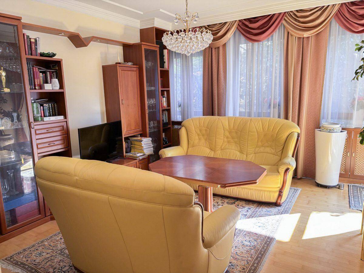 Gemütliches Wohnzimmer mit gelben Sofas, Parkettboden und dekorativen Vorhängen.