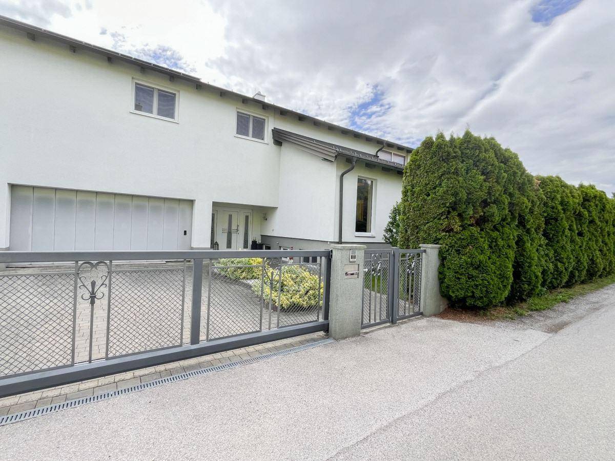 Vorderansicht des Hauses mit Einfahrt, modernem Tor und gepflegter Hecke.
