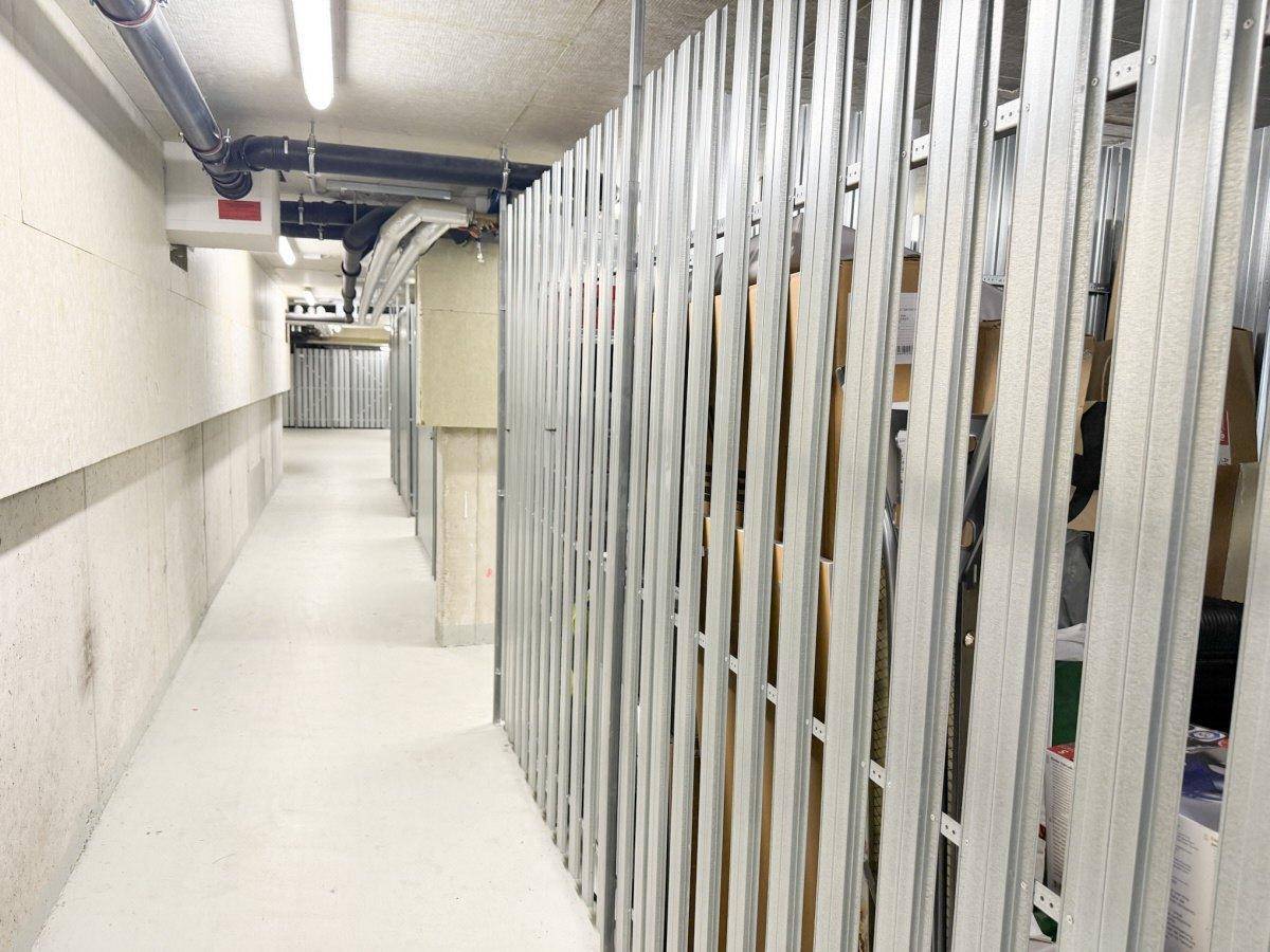 Kellerabteil mit Metallgittern und gelagerten Gegenständen in einem sauberen Untergeschoss.