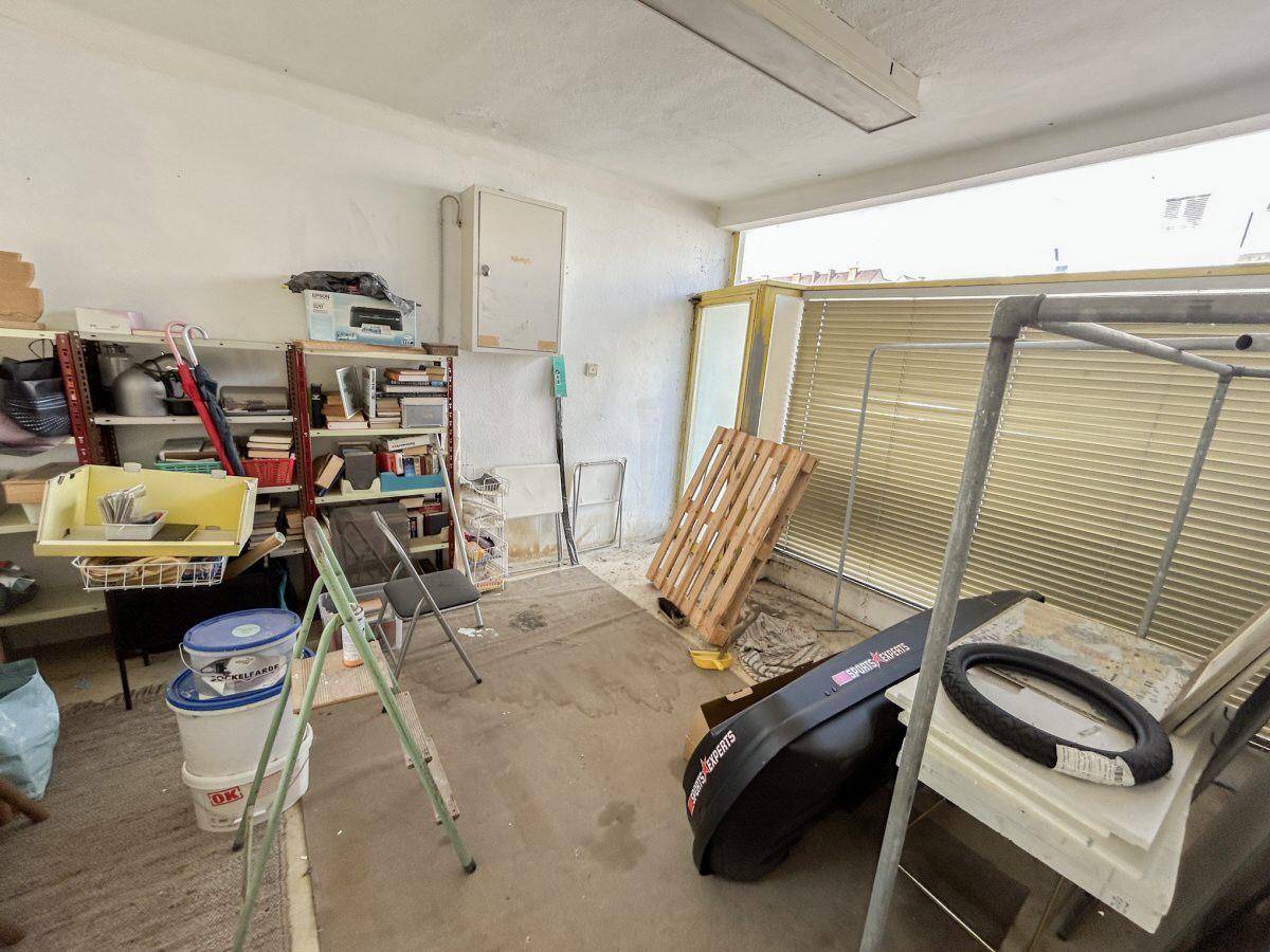 Lagerraum mit Regalen, einem Fenster und verschiedenen Gegenständen, wirkt funktional und hell.