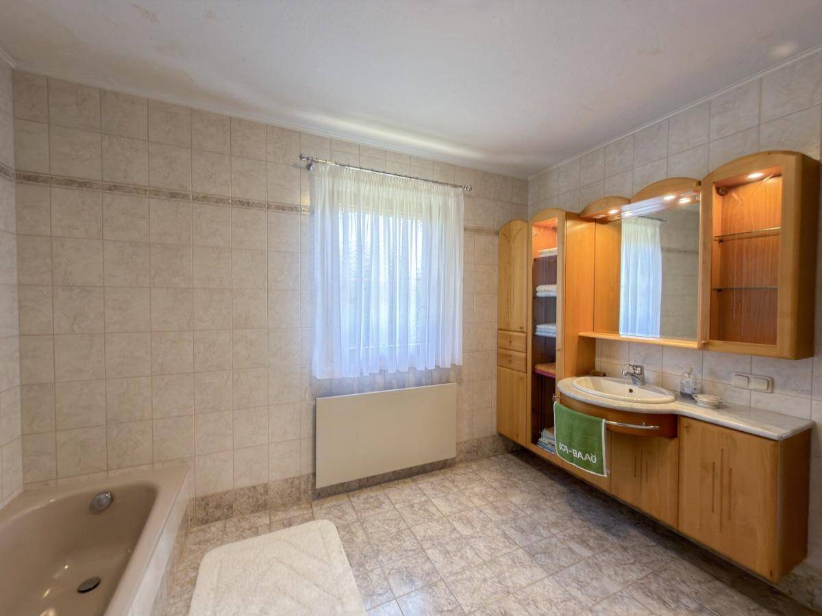 Badezimmer mit Holzwaschtisch, Spiegelschrank und beigefarbenen Fliesen.