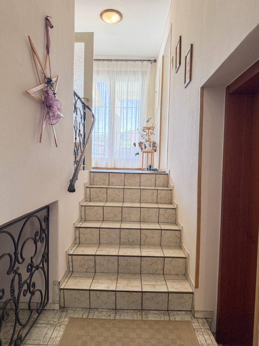Geflieste Treppe mit schmiedeeisernem Geländer führt in das obere Stockwerk des Hauses.