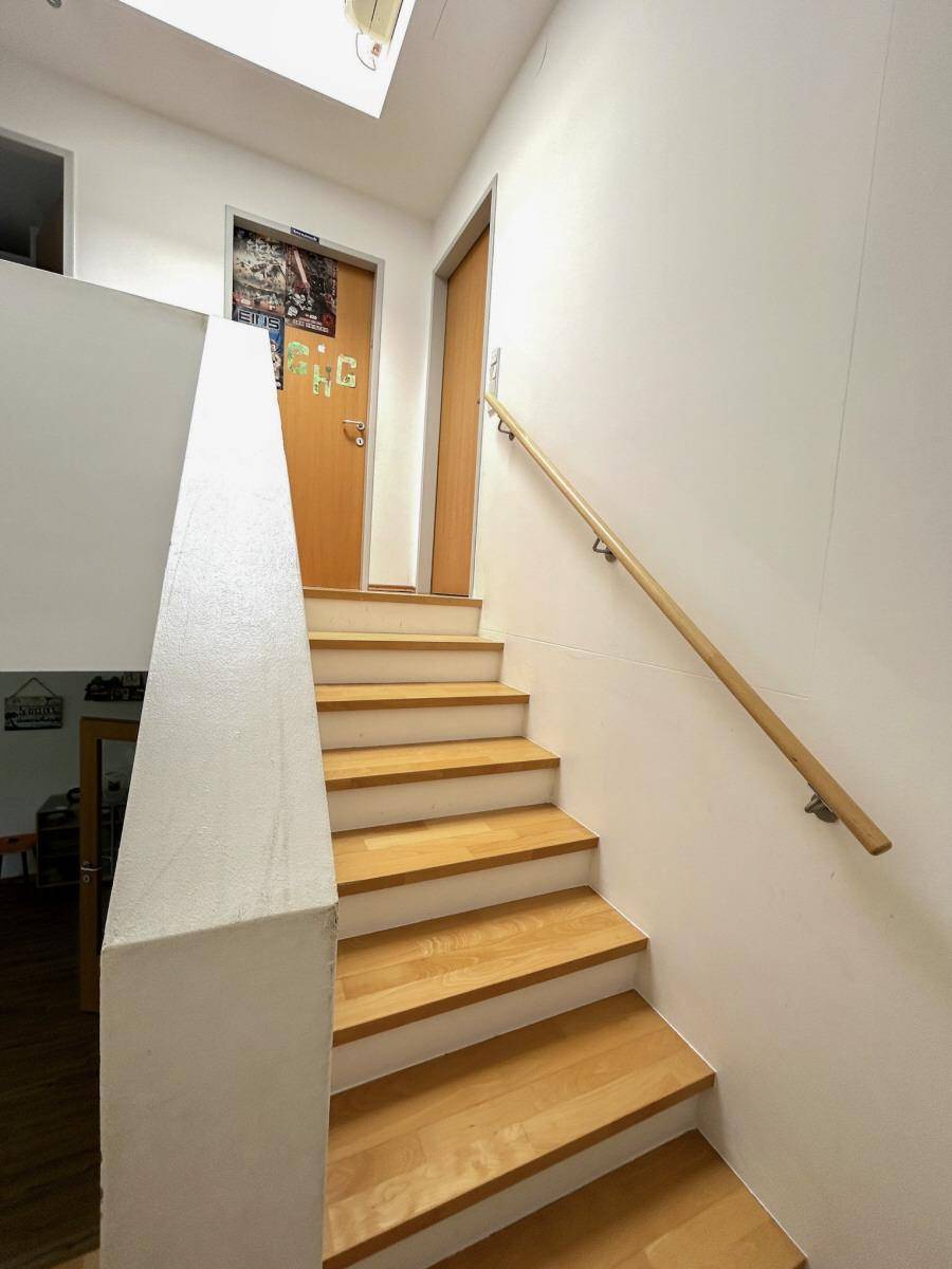 Treppenaufgang mit Holzstufen und Handlauf, der die verschiedenen Etagen verbindet.