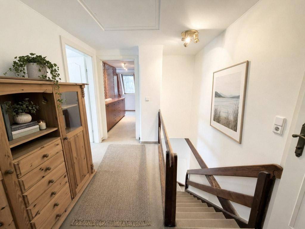 Heller Flur mit Holzschrank und Treppe, die zu den oberen Etagen führt.