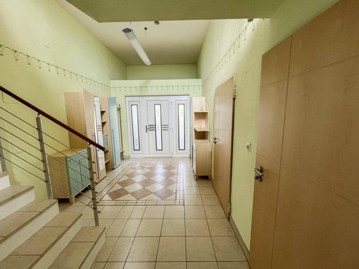 Heller Eingangsbereich mit Fliesenboden, Garderobenschränken und Treppenaufgang.