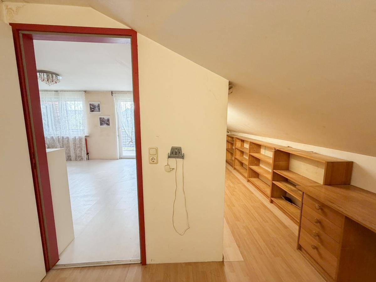 Arbeitszimmer im Dachgeschoss mit Dachschräge, Regalen und Schreibtisch.