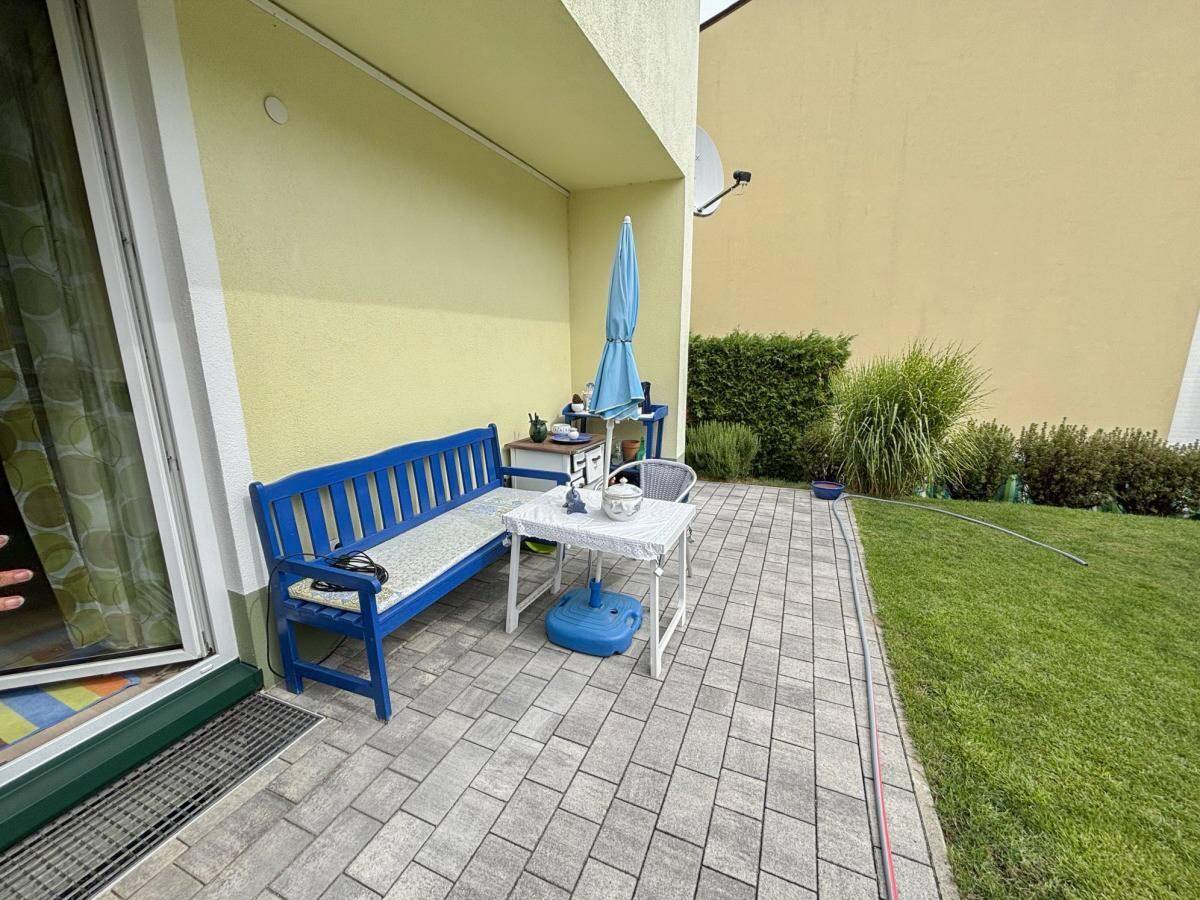 Geräumige Terrasse mit direktem Zugang zum Garten, ausgestattet mit Sitzgelegenheiten und Sonnenschirm.