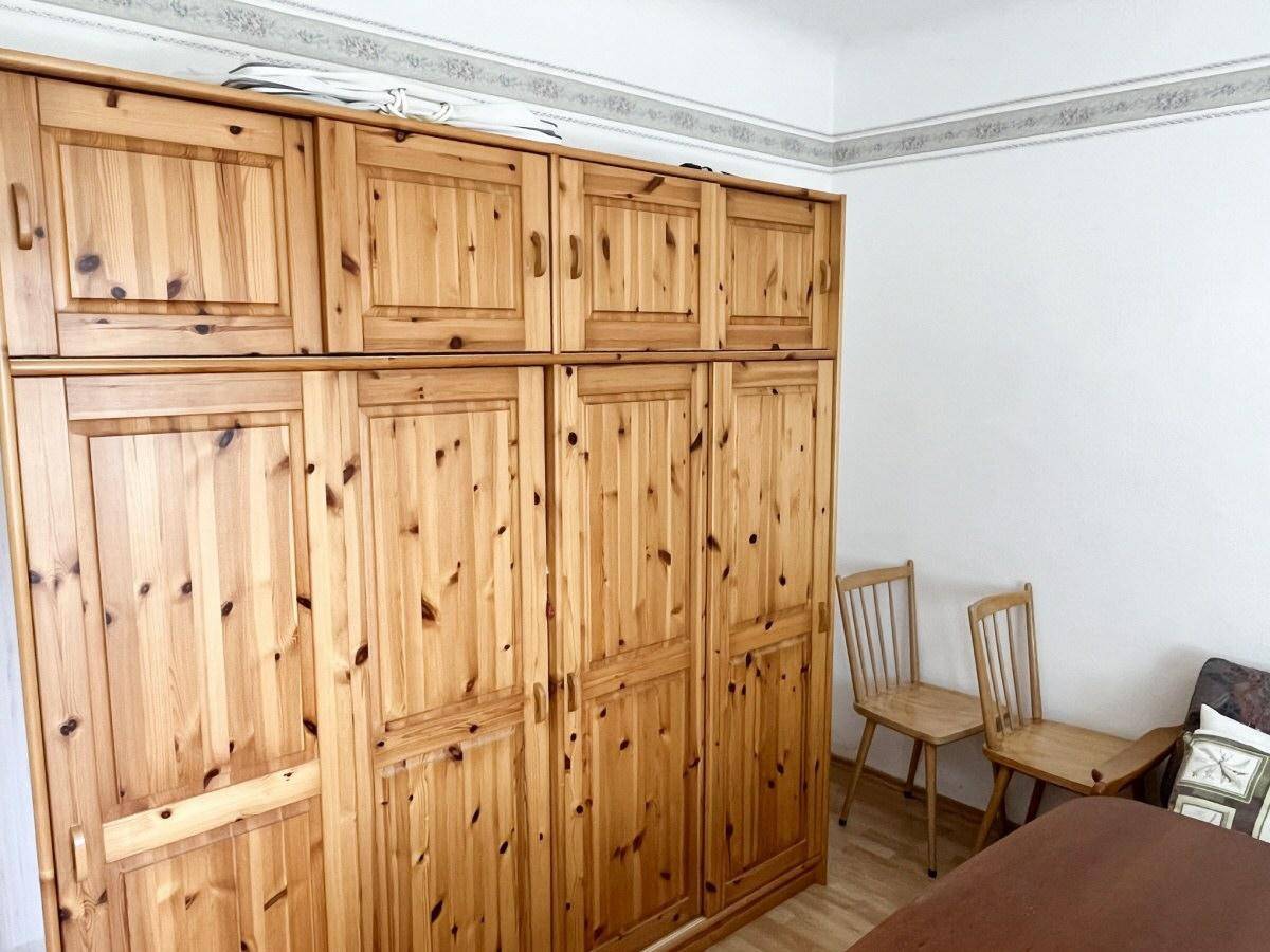 Großer Kleiderschrank aus hellem Holz mit vielen Türen und Fächern in einem Innenraum.
