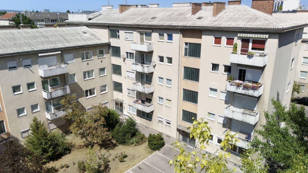 Mehrfamilienhaus mit mehreren Balkonen und einem begrünten Innenhofbereich.