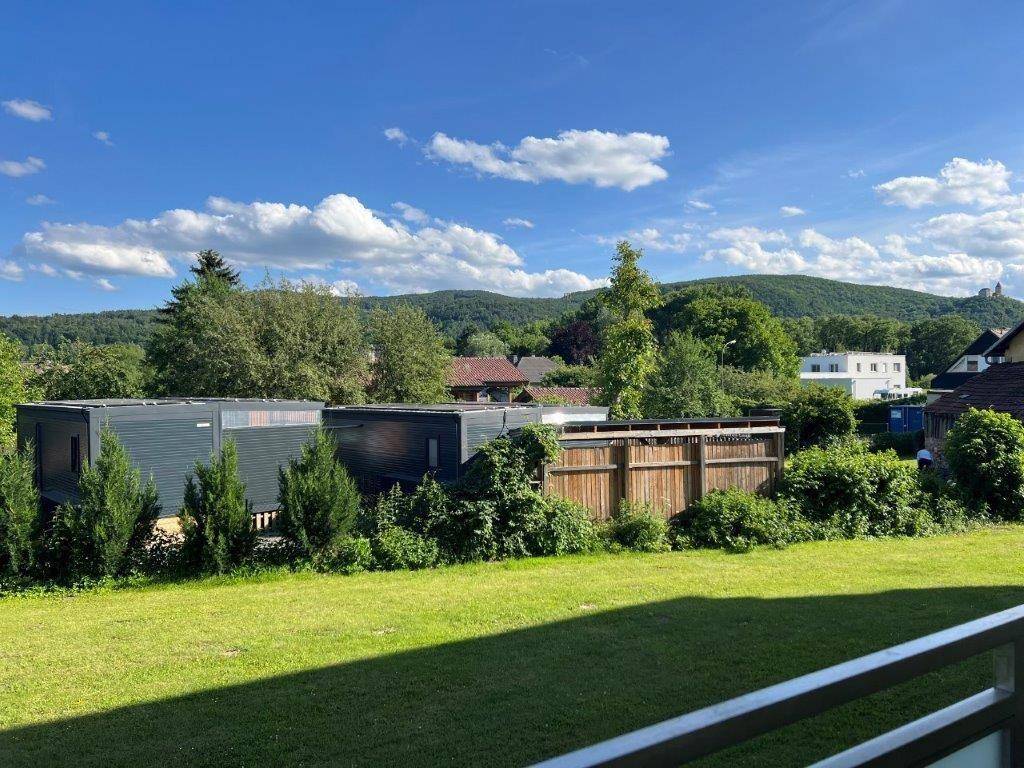 Balkon mit Blick ins Grüne und auf die umliegende Hügellandschaft unter blauem Himmel.