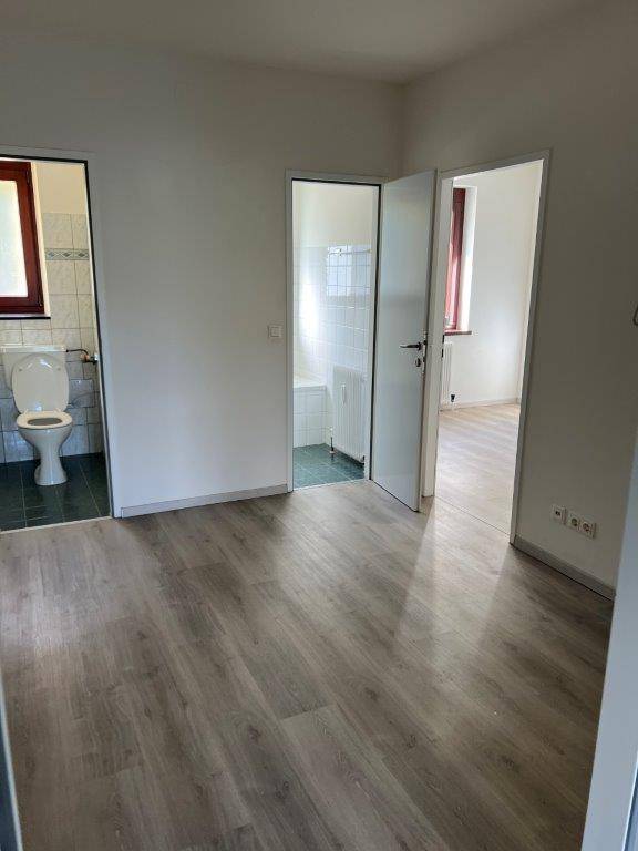 Innenbereich mit Laminatboden und Blick auf mehrere Türen zu angrenzenden Räumen.