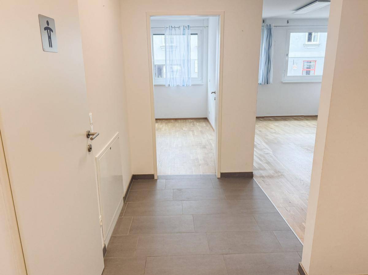 Flur mit Fliesenboden, der den Blick in zwei helle Zimmer mit Parkett freigibt.