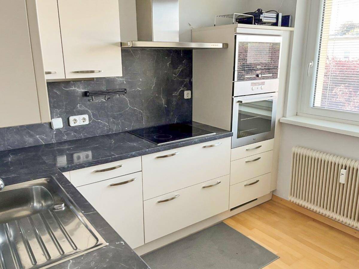 Detailansicht der modernen Küche mit Induktionskochfeld, Backofen und Dunstabzugshaube.