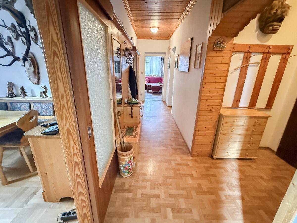 Langer Flur mit Holzvertäfelung, Parkettboden und traditionellen Möbeln.