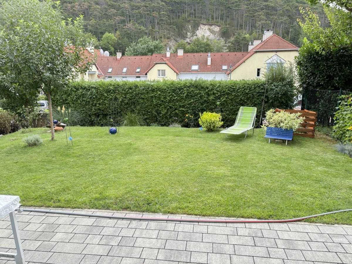 Gepflegter Gartenbereich mit Rasenfläche, Hecke und Blick auf die umliegende Hügellandschaft.