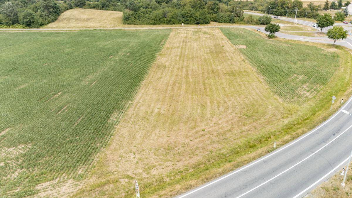 Luftaufnahme eines großen Grundstücks mit Feldern und einer kurvigen Straße, umgeben von Natur und Bebauung.