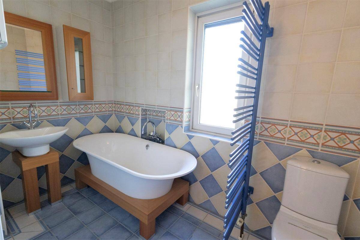 Modernisiertes Badezimmer mit freistehender Badewanne, blauen Fliesen und Handtuchheizkörper.
