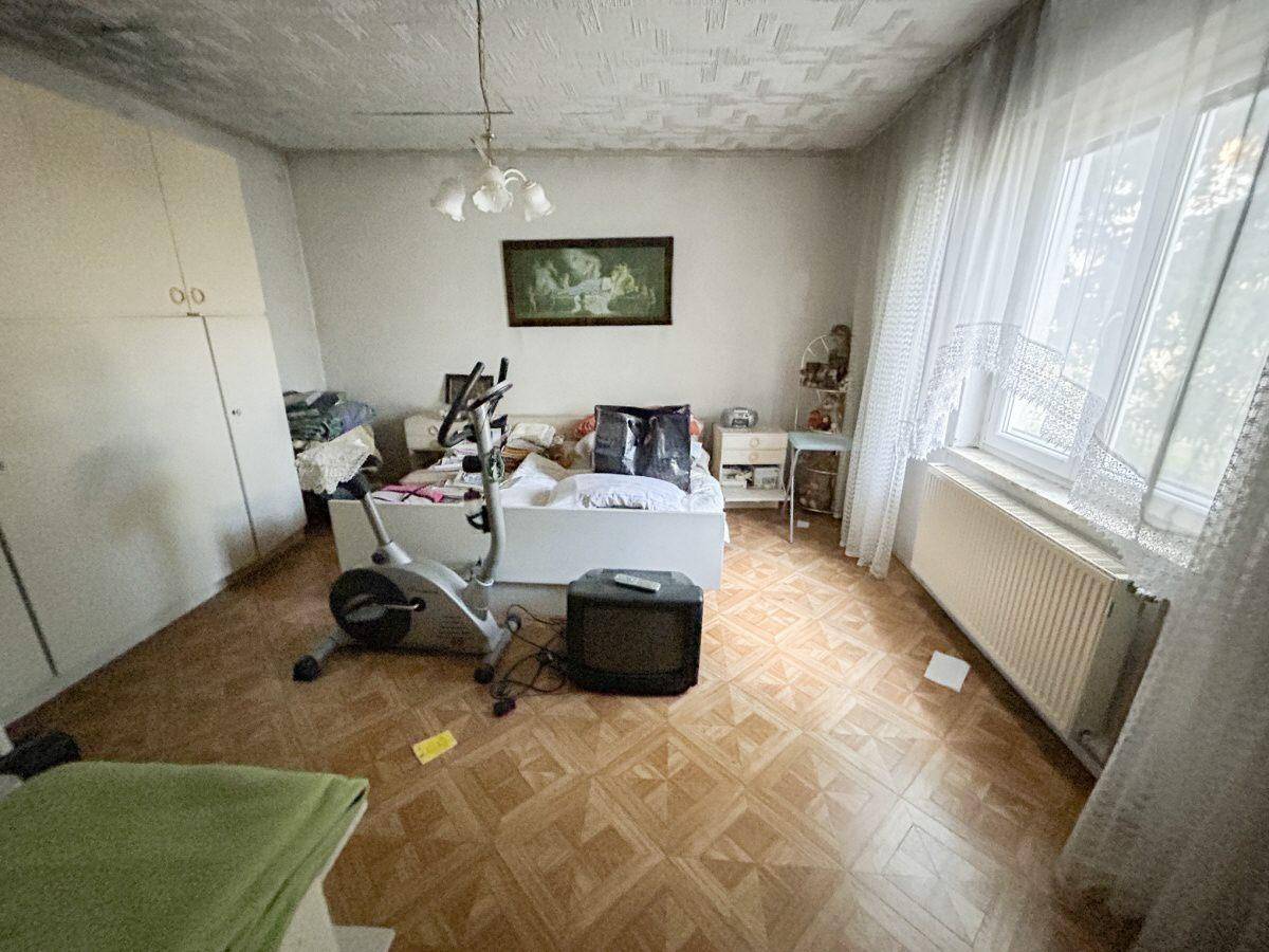 Schlafzimmer mit gemustertem Boden, einem Fitnessrad und einem Fenster mit Vorhängen.