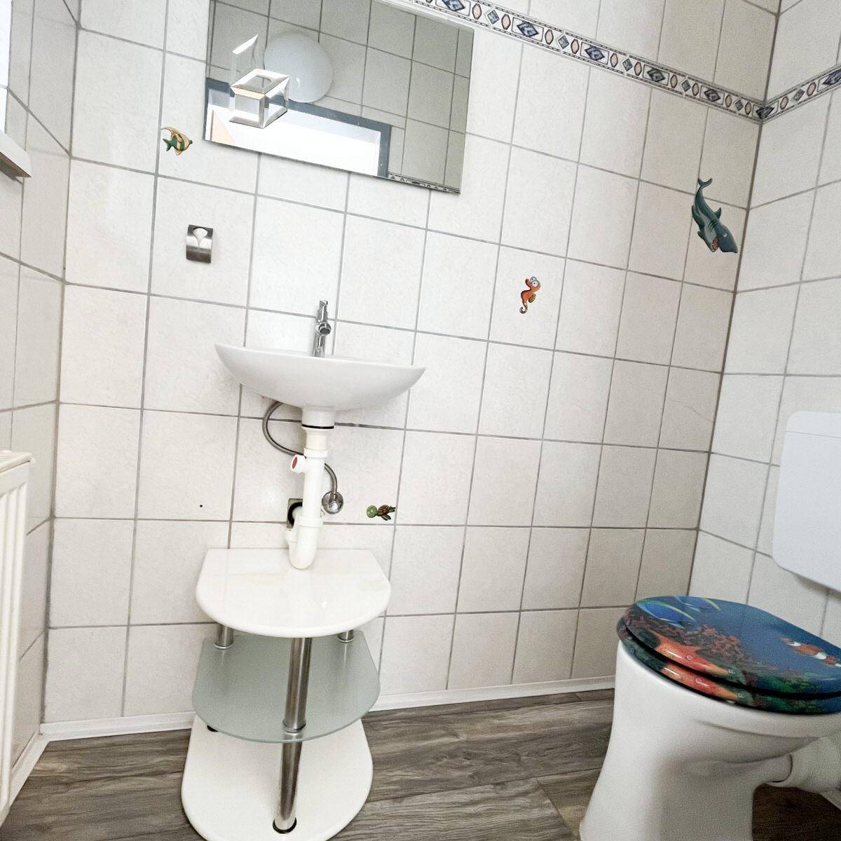 Gäste-WC mit Waschbecken, Toilette und verspielten Fliesen, hell und sauber.