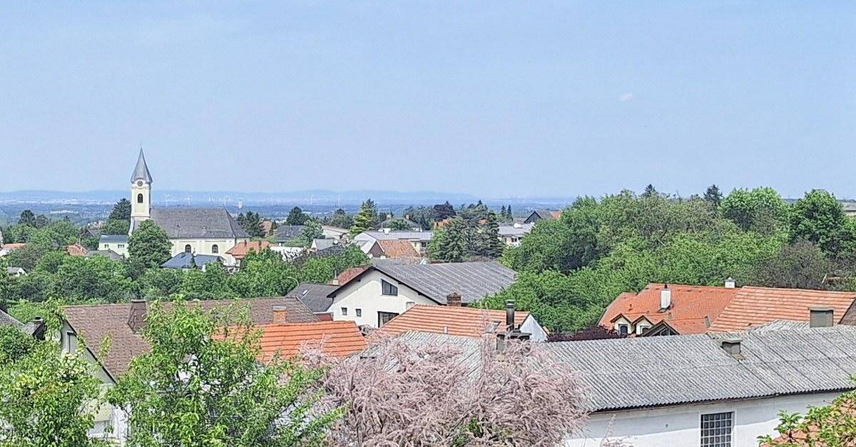 Panoramablick über ein malerisches Dorf mit Kirche und weitem Horizont in ländlicher Umgebung.