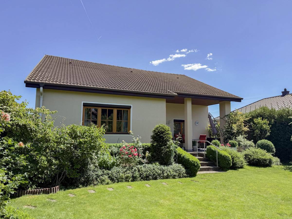 Ansicht des Einfamilienhauses von der Gartenseite mit gepflegter Rasenfläche.