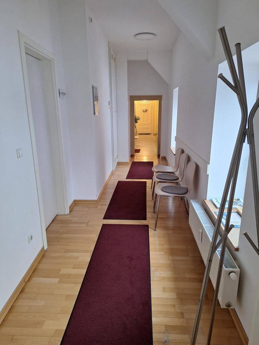 Langer, heller Flur mit Holzboden, weißen Wänden und mehreren Türen, der zu weiteren Räumen führt.