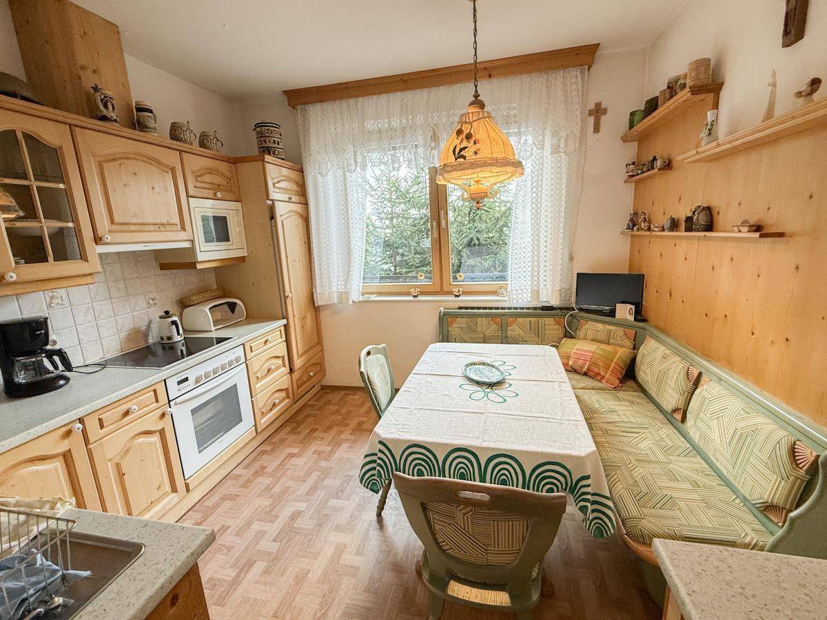 Traditionelle Küche mit Holzeinbauten, Essbereich und Blick ins Grüne.