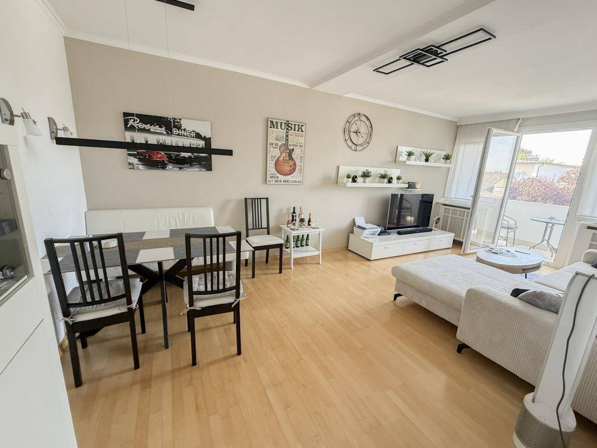 Heller Wohn- und Essbereich mit Holzfußboden, bequemer Couch und Zugang zum Balkon.