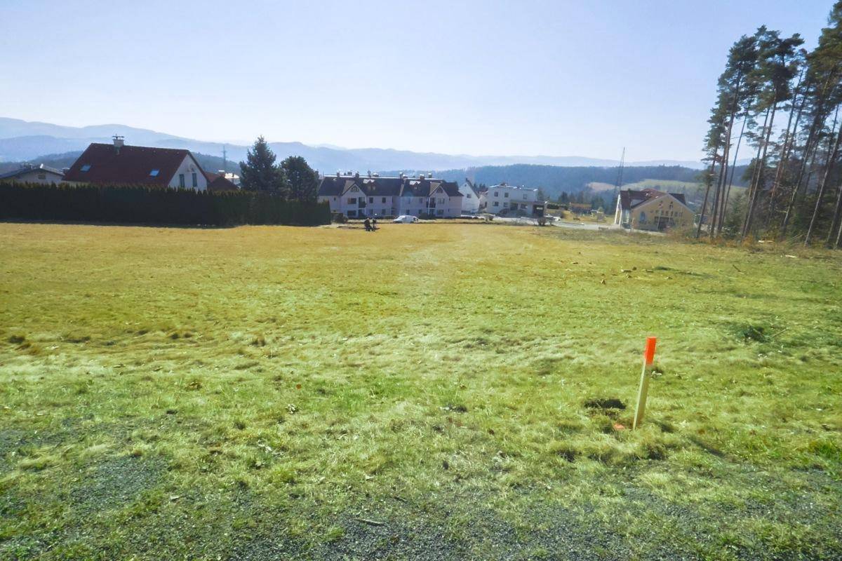 Sonniges, weitläufiges Wiesengrundstück mit Fernblick auf die umliegende Bebauung und Bergketten.