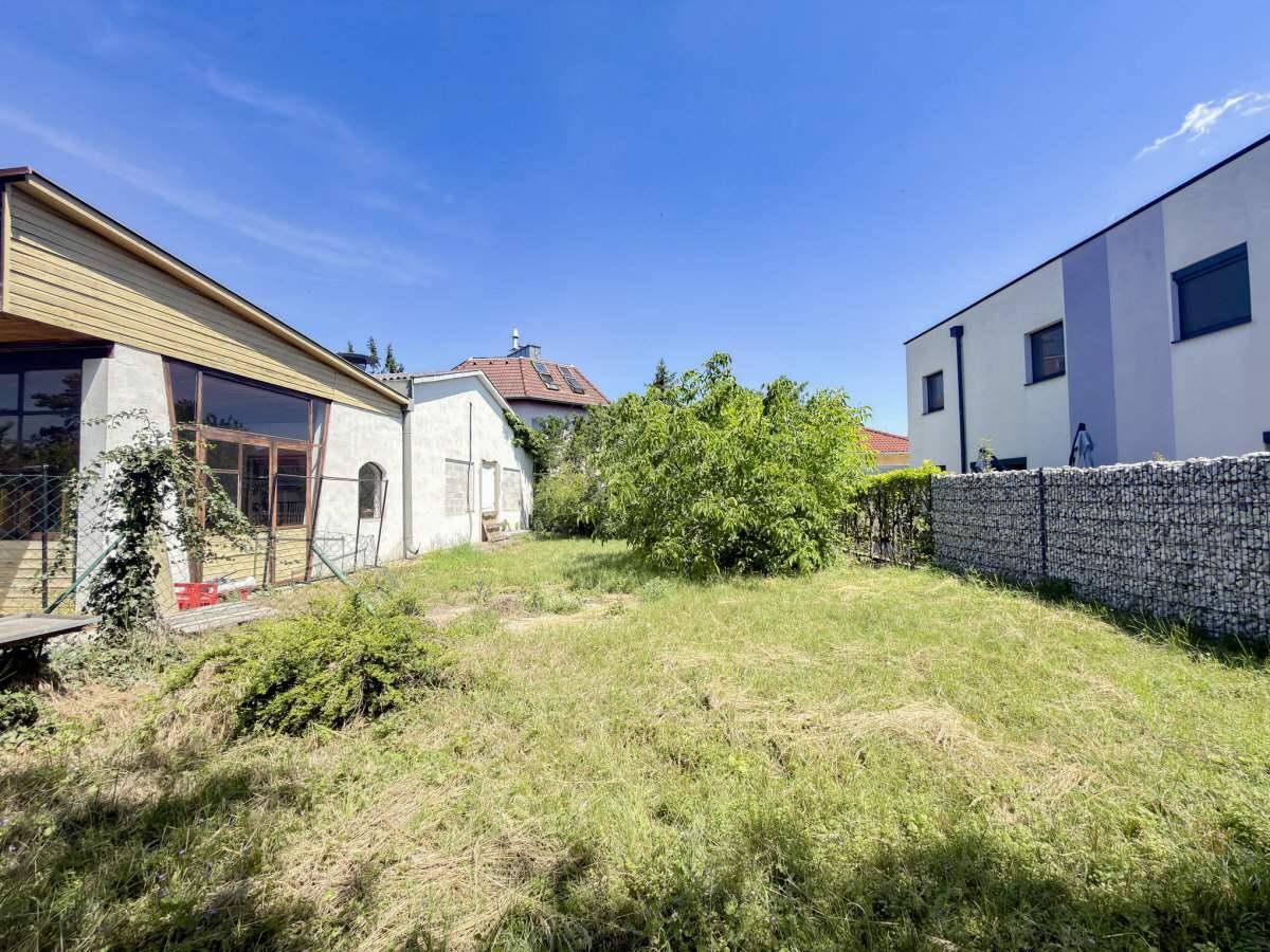 Weitläufiger Gartenbereich mit Rasen, Bäumen und angrenzenden Gebäuden.