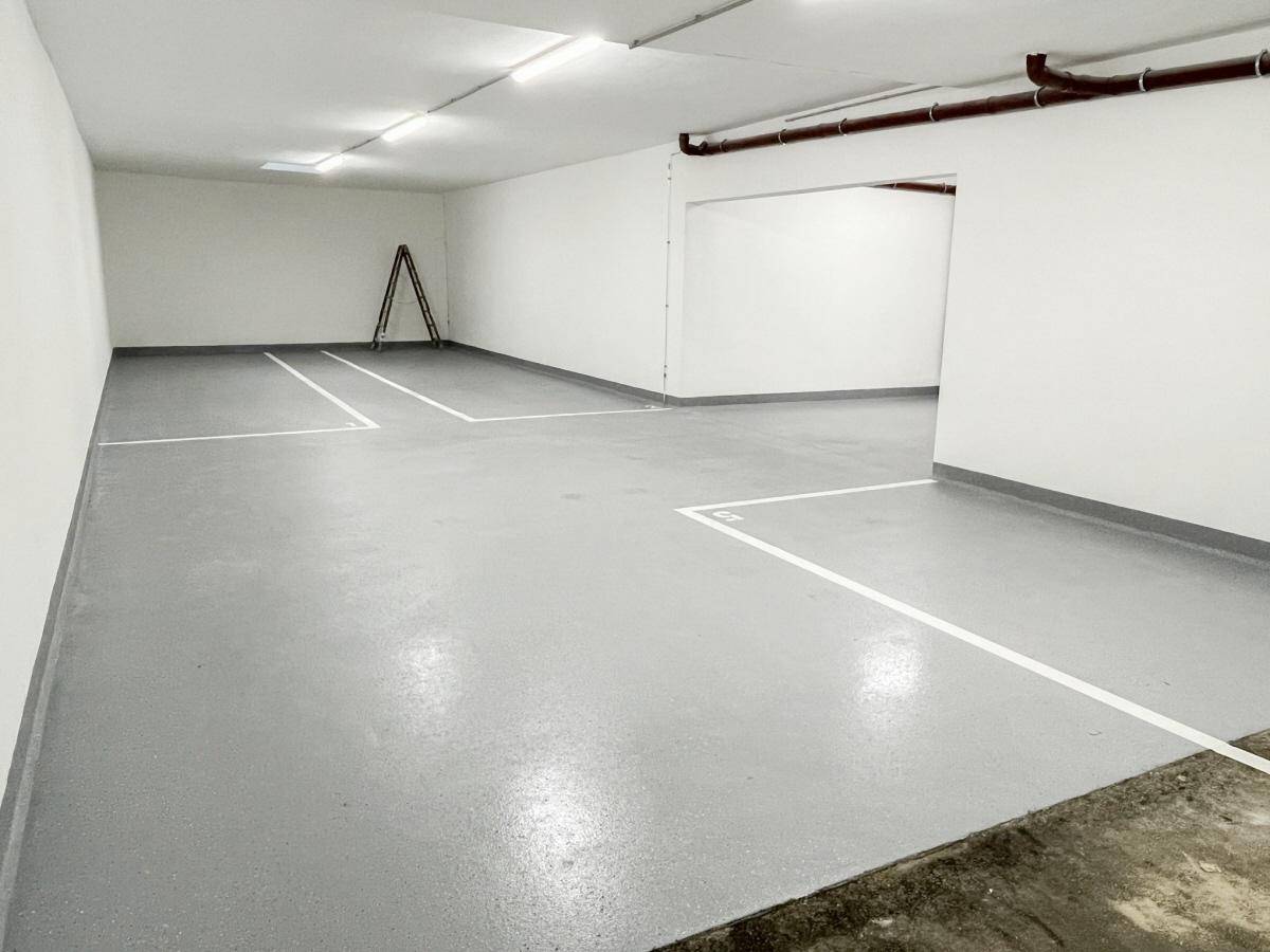 Saubere und helle Tiefgarage mit klar markierten Parkflächen und funktionaler Beleuchtung.