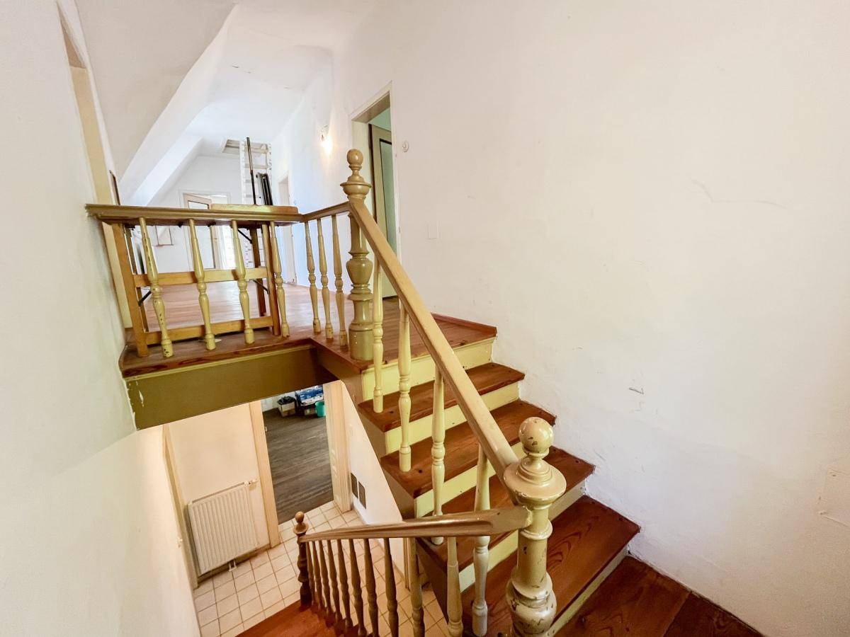 Helles Treppenhaus mit Holzgeländer und Blick auf die obere Etage.