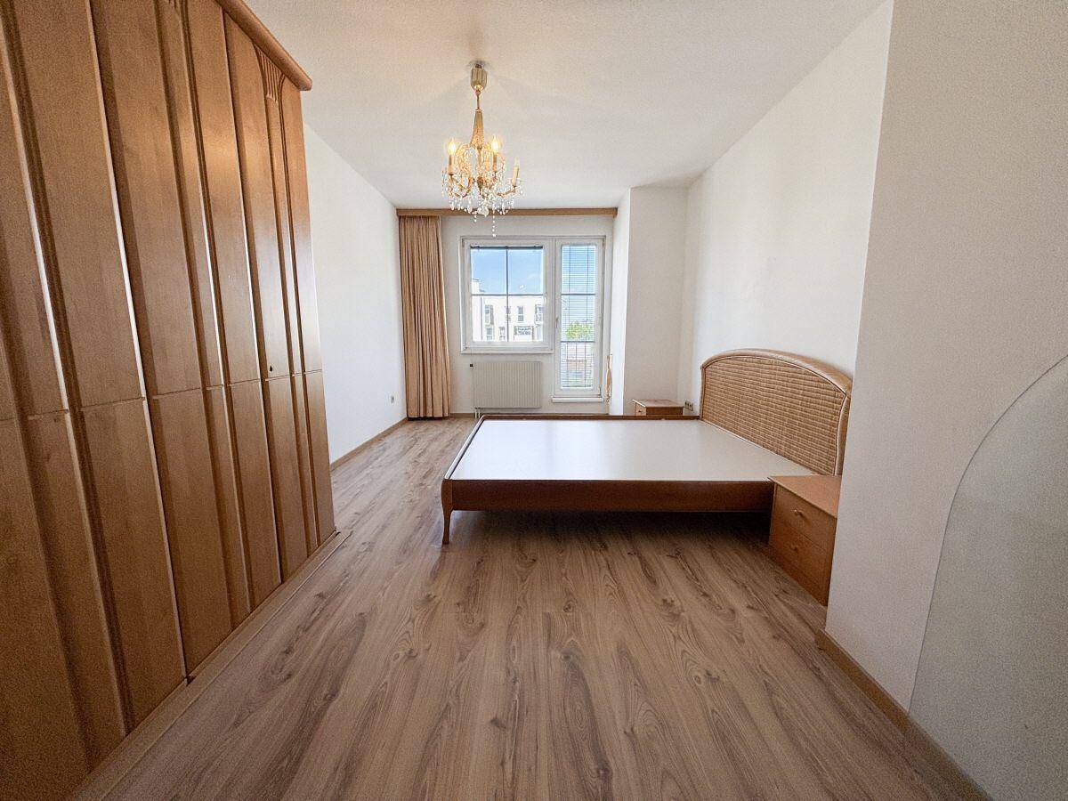 Schlafzimmer mit Laminatboden, Doppelbett und großem Kleiderschrank.
