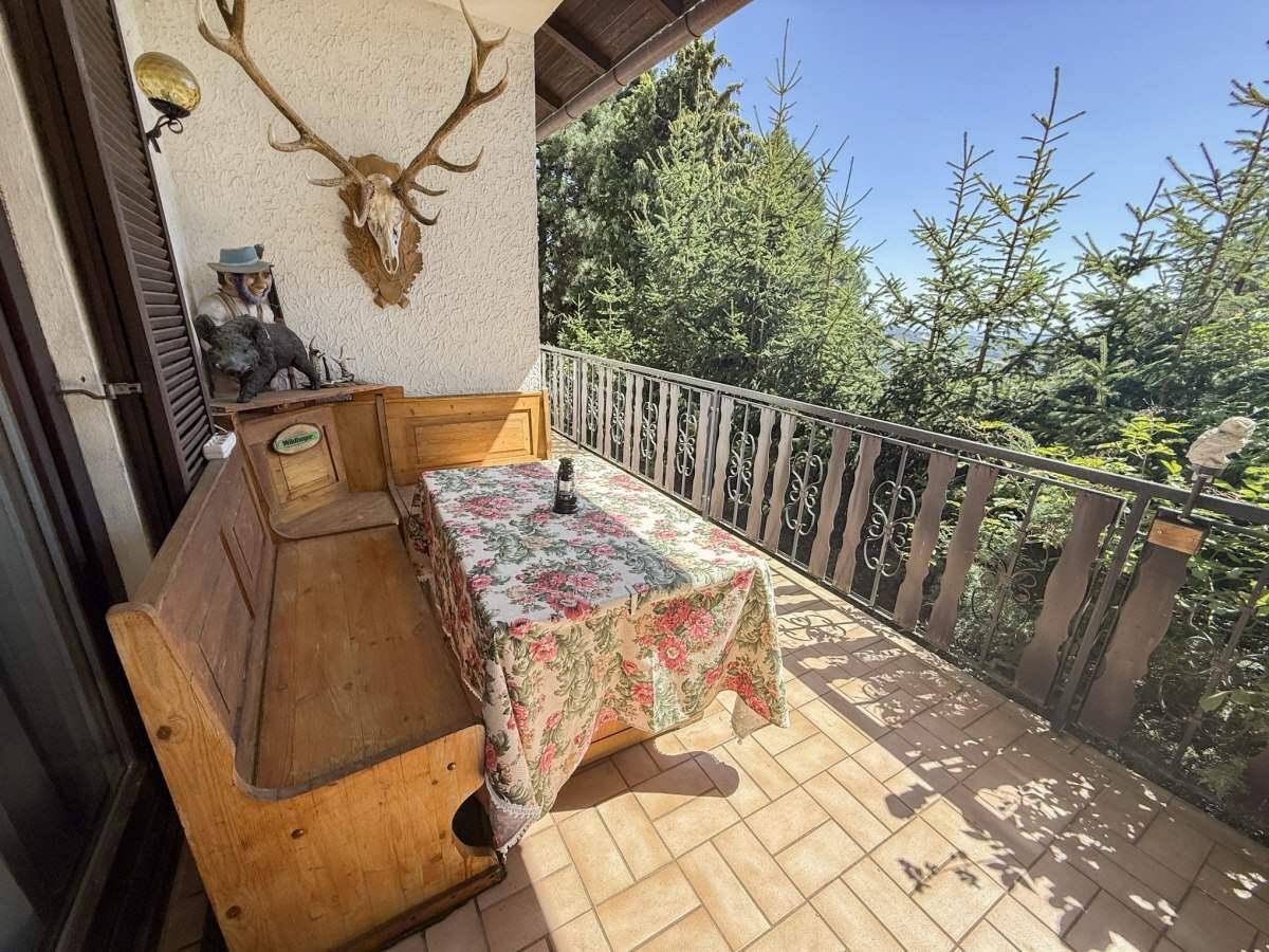 Sonniger Balkon mit traditioneller Sitzbank, Tisch und Bergblick.