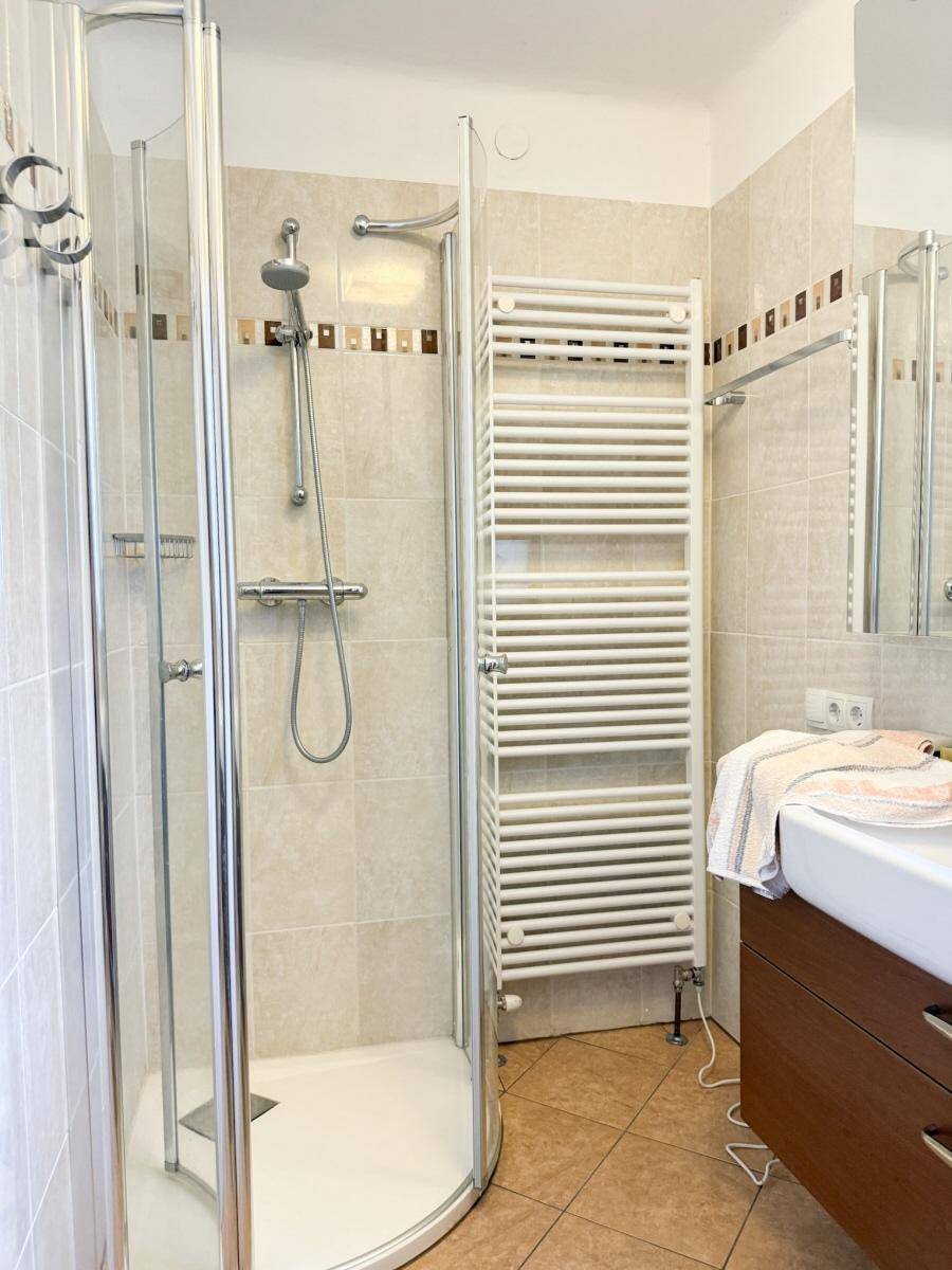 Modernes Badezimmer mit Eckdusche, Einzelwaschbecken und beheiztem Handtuchhalter.